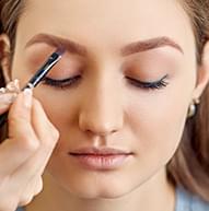 Model with closed eyes applying the light brown pomade