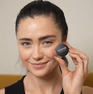 Model with thick dark brows holding the pomade